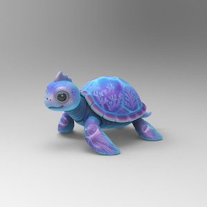 May include: A whimsical, stylized turtle figurine in shades of blue and purple. The turtle has a detailed shell with a floral pattern, large eyes, and a small fin on its head. The figurine is set against a plain, light gray background.