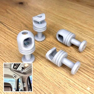 Peut inclure: Quatre clips de garniture intérieure de voiture en plastique gris clair. Chaque clip a un corps cylindrique avec une base circulaire et un dessus fendu. Une petite image montre un clip installé dans le ciel de toit d'une voiture.