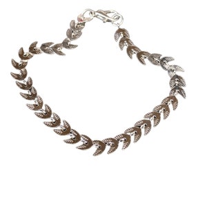 May include: A silver chain bracelet with a leaf-shaped design. The chain is made of small, interconnected leaves that create a flowing, organic look.