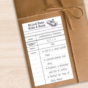 以下が含まれることがあります： 「Blind Date With A Book」と書かれたラベルが付いた、茶色の紙で包まれたパッケージ。ラベルには、ジャンルがコンテンポラリーロマンス、Goodreadsの評価、ページ数が記載されています。手がかり：海辺の町、書店。