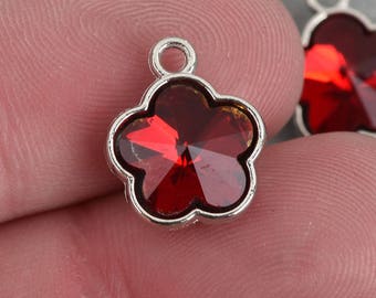 Puede incluir: Dos abalorios de plata en forma de flor con centros de cristal rojo. Los abalorios tienen un bucle en la parte superior para sujetarlos a joyas.
