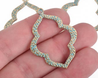 Puede incluir: Primer plano de tres colgantes calados de metal con forma de cuadrifolio. Los colgantes tienen un acabado dorado con una incrustación de esmalte azul turquesa texturizado. Cada colgante tiene un pequeño lazo en la parte superior.