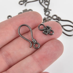 May include: Two silver-toned metal jewelry clasps. One is a hook clasp and the other is a toggle clasp.