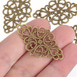 May include: A set of four antique gold metal filigree charms with a diamond-shaped design. The charms have a delicate, intricate pattern and are perfect for adding a touch of vintage elegance to jewelry or crafts.