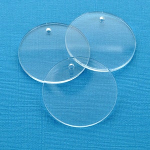 May include: Three clear plastic circles with holes in the center. The circles are stacked on top of each other.