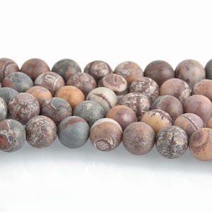 May include: A strand of round, matte-finish gemstone beads in shades of brown, gray, and tan. The beads have a natural, earthy appearance with unique patterns and textures. Ideal for jewelry making.