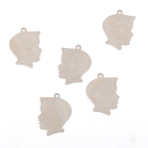 May include: Five silver metal charms shaped like a person's profile. The charms are blank and have a hole at the top for attaching to a necklace or bracelet.