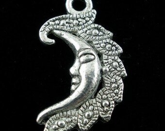 May include: Silver-toned crescent moon pendant with a serene face, adorned with detailed leaf-like embellishments. The pendant has a loop at the top for easy attachment. A celestial-themed charm for jewelry making or crafting.