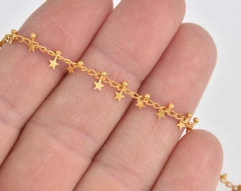 May include: Gold-colored chain necklace with small star charms. The delicate chain features tiny star pendants evenly spaced along its length. The necklace is shown against a light background.