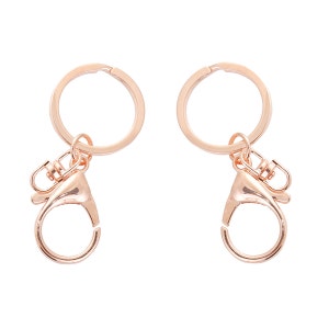 May include: Two rose gold keychains with a round ring and a lobster clasp.