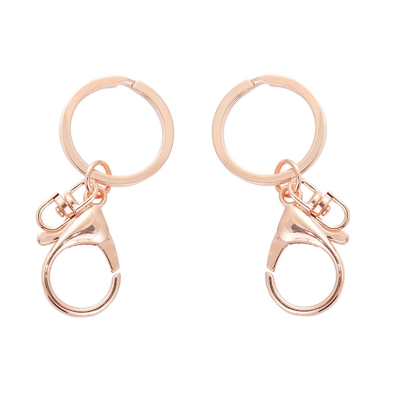 May include: Two rose gold keychains with a round ring and a lobster clasp.