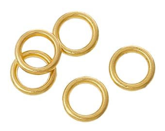 May include: Several gold-colored jump rings of varying sizes are scattered against a white background. The rings are circular with a smooth, polished finish, reflecting light. These jewelry findings are used for connecting jewelry components.