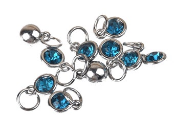 May include: A group of silver charm pendants with blue crystal accents. The charms are linked together with silver rings.