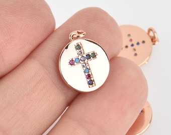 May include: A rose gold pendant charm featuring a cross with colorful gemstones. The cross is set against a round, smooth background.