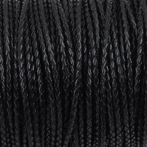 May include: A close-up of a spool of black braided leather cord. The cord has a textured, diamond-shaped pattern.