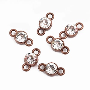 May include: Five antique copper-toned connector charms with clear crystal rhinestones. Each charm has two loops for attaching to jewelry.