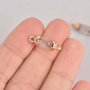 May include: Gold-tone connector with a clear crystal tube. The connector has two loops on either end.