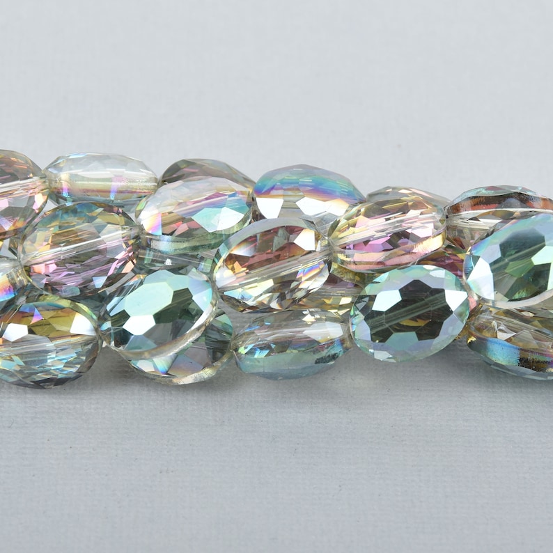 Pode incluir: Um fio de contas de vidro ovaladas iridescentes. As contas t&ecirc;m um design facetado e s&atilde;o enfiadas em um fio transparente.