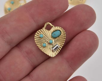 May include: Gold heart-shaped pendant with turquoise and clear rhinestones. The pendant has a textured surface and a loop at the top for attaching a chain.