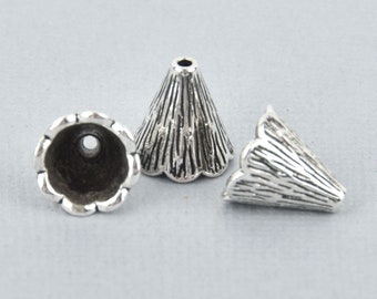 May include: Three silver-colored cone-shaped bead caps with a textured, ridged design. The bead caps have a scalloped edge at the base and a small hole at the top. The caps are likely used for jewelry making.