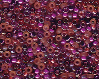 May include: Assortment of seed beads in various shades of purple, red, and brown. The beads are mostly round, with some square and oval shapes. The beads have a shiny, iridescent finish.