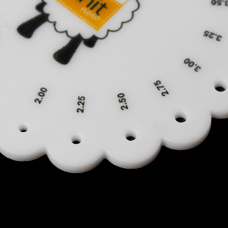 May include: A white plastic knitting gauge with a scalloped edge and black text indicating needle sizes from 2.00 to 3.50. The gauge features a sheep graphic and the text "knit now".