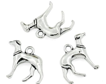 May include: Three silver-colored dog charms. Each charm depicts a slender dog with a collar and a loop for attaching to jewelry or other crafts. The dogs are in different poses, with one lying down and the others standing.