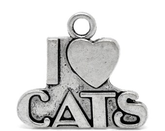 May include: A silver-toned charm with the phrase "I ❤️ CATS." The heart symbol is above the word "CATS." The charm has a loop at the top for attaching to a necklace or bracelet. The charm is made of metal and has a slightly aged appearance.