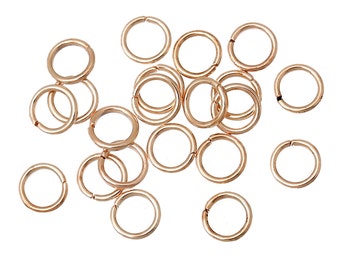 May include: A collection of rose gold jump rings, scattered against a white background. The rings are circular, with a small opening for attaching to other jewelry components. The metal has a shiny, reflective surface, and the overall aesthetic is delicate and feminine.