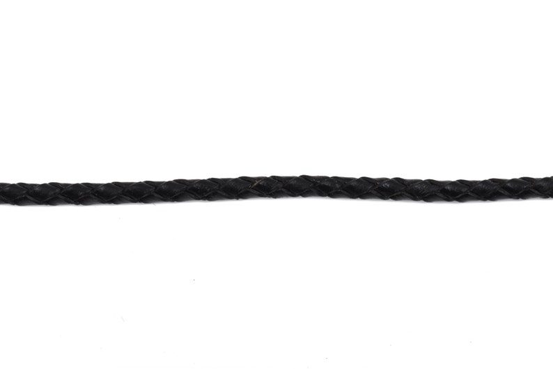 May include: A close-up of a black braided leather cord.