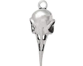 May include: Silver-toned pendant in the shape of a bird skull. The pendant features a detailed design of the skull's features, including eye sockets, nasal cavity, and beak. The pendant has a loop at the top for attaching to a chain or cord.