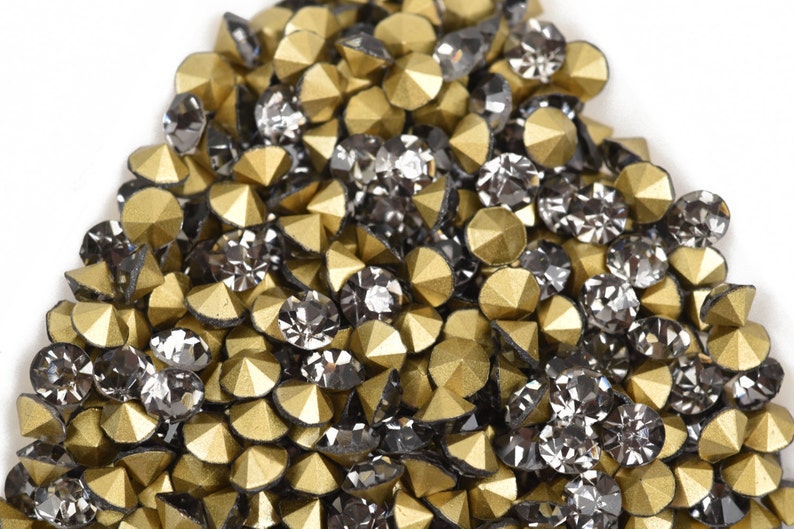 May include: A pile of gold and black rhinestones, with a pointed, faceted design.