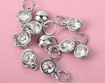 May include: A group of silver-toned metal charms with clear rhinestone accents. Each charm features a small loop for attaching to a bracelet or necklace.