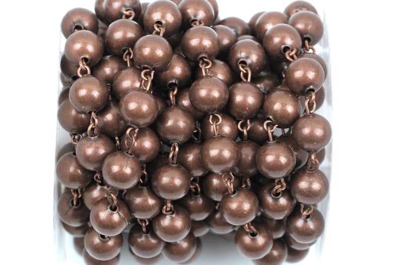 May include: A roll of copper-colored chain with round beads. The chain is made of metal and the beads are smooth and shiny.