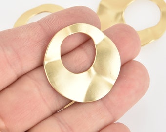 May include: A set of three gold-toned metal rings with a wavy, irregular shape. The rings have a smooth, polished finish and a large, open circle in the center.