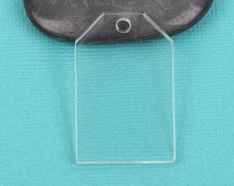 May include: A clear, rectangular acrylic tag with a small hole at the top for hanging. The tag has a transparent appearance and is set against a teal background. The tag is a blank slate, ready for customization.
