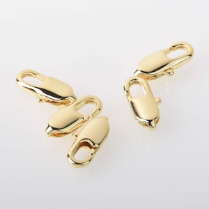 May include: Two gold-toned metal lobster clasps, each with a spring-loaded opening and a secure closure. These clasps are commonly used for jewelry making and crafting.