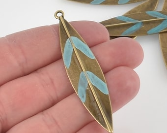May include: Antique bronze leaf charm with a turquoise blue painted design. The leaf charm has a hole at the top for hanging.
