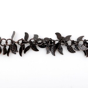 May include: A chain necklace with small, dark brown metal leaves hanging from it. The leaves are arranged in a cascading pattern, creating a delicate and feminine look.
