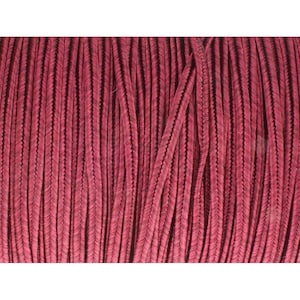 May include: Close-up of a spool of burgundy-colored cord. The cord has a braided appearance with a dark, almost black, center. The texture is visible, with vertical lines creating a pattern. The cord is tightly wound, suggesting it is new and unused.