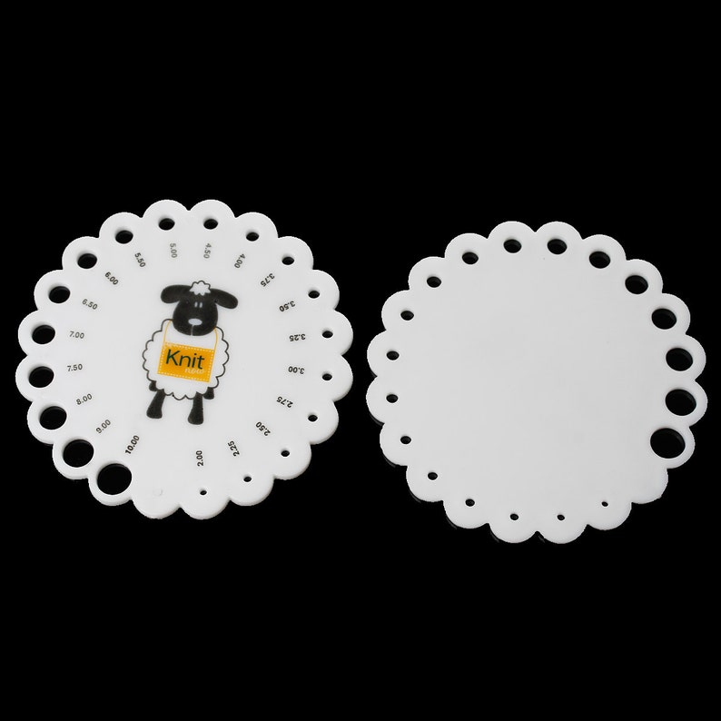 May include: Two white plastic knitting gauge tools. One features a black and white sheep graphic with the word "Knit" on a yellow tag. The gauge has numbered holes for measuring needle sizes. The other gauge is blank.