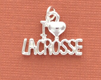 May include: A silver charm with the words "I LOVE LACROSSE" in capital letters. The word "I" is connected to a heart shape, and the charm is on a textured, reddish-brown background.