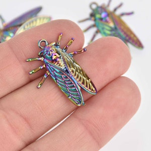 May include: A rainbow iridescent metal cicada charm with detailed wings and legs. The charm has a loop at the top for attaching to jewelry or other crafts.