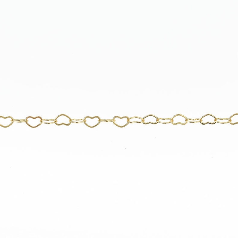 Pu&ograve; includere: Una delicata catena color oro con un motivo ripetuto di maglie a forma di cuore. La catena &egrave; presentata su uno sfondo bianco, evidenziando il design intricato e il tono caldo del metallo. Questa catena di gioielli &egrave; adatta per collane e bracciali.