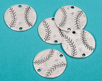 May include: Several silver-toned baseball charm pendants with black stitching details. Each charm is round with two holes for stringing. The charms are scattered on a turquoise background.