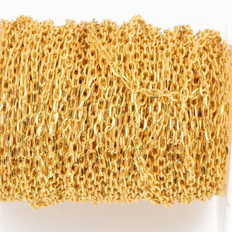 May include: A spool of gold-colored chain. The chain is made of small, oval-shaped links. The chain is tightly wound around the spool. The chain is a bright, shiny gold color.