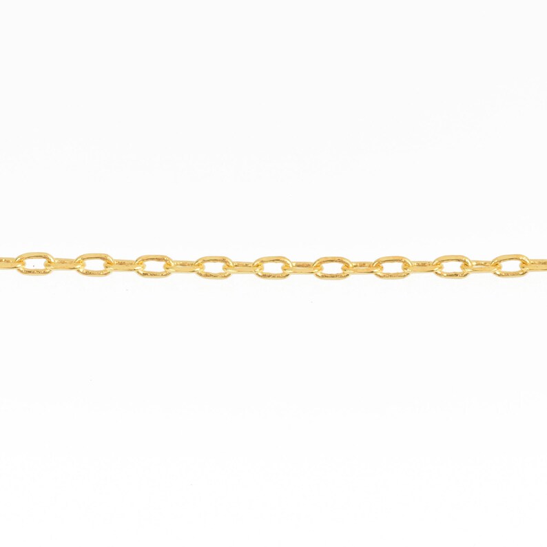 May include: A close-up of a gold-colored chain against a white background. The chain is composed of small, oval-shaped links. The chain is a jewelry item.