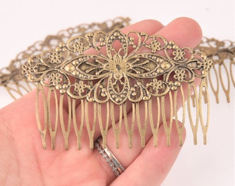 May include: An antique bronze-colored hair comb with an ornate floral design. The comb features a central flower motif with delicate filigree and multiple teeth for securing hair. The comb is likely made of metal and is designed for decorative use.