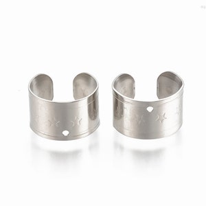 May include: Two silver metal rings with a star pattern and a small hole on the side.