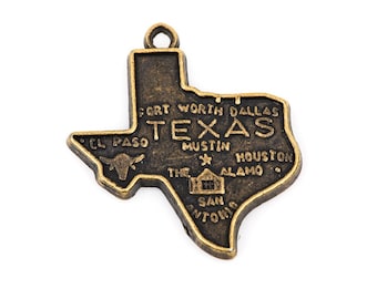 May include: A gold-toned metal charm shaped like the state of Texas. The charm features the words "Texas", "Fort Worth", "Dallas", "El Paso", "Austin", "Houston", "The Alamo", and "San Antonio".